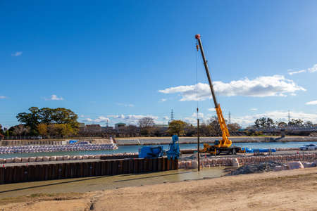 Mobile crane lifting a long steel material at construction site