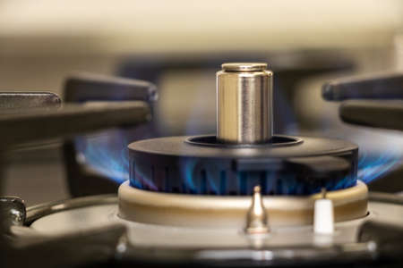 Close up on a gas burner that burns with blue flameの写真素材