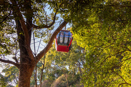 Red gondola on the ropeway passing through the mountainの写真素材