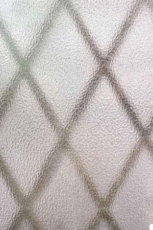 The pattern of the window grate seen through frosted glass