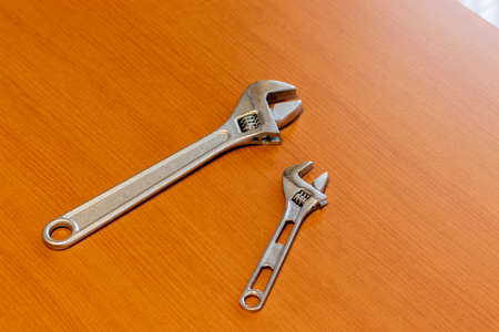Two adjustable wrenches on a wooden board