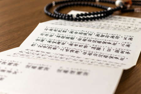 Buddhist sutra and rosary on a wooden deskの写真素材