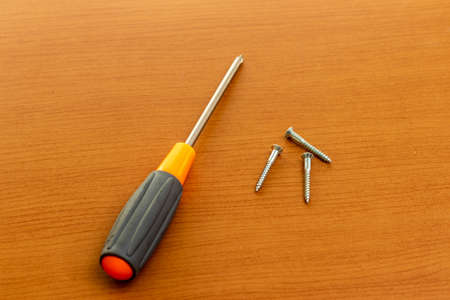 Screws and screwdriver on the wooden boardの写真素材