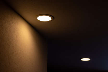 Two downlights in the ceiling that illuminate the dark corridorの写真素材