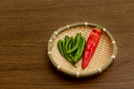 Red chili pepper and green chili peppers on a bamboo colanderの写真素材