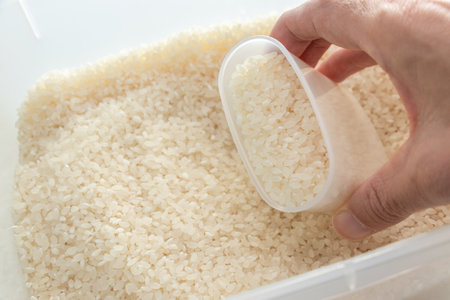 Scoop the rice in the rice bin with a measuring cupの写真素材