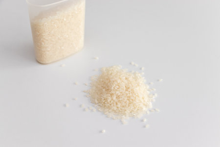 White rice grains and a plastic measuring cupの写真素材
