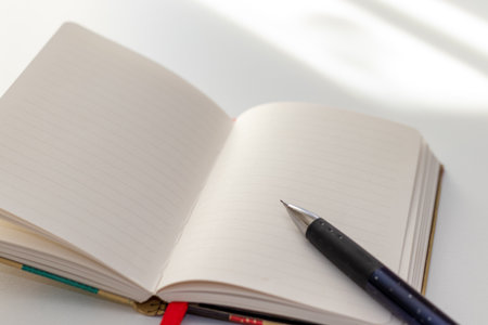 A notebook and a pen on the desk by the windowの写真素材