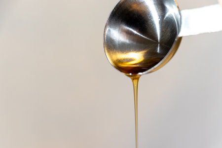 Oil dripping from a metal spoonの写真素材
