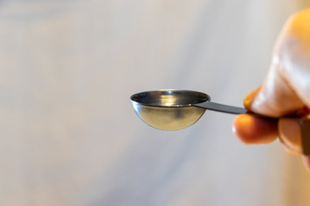 Metal measuring spoon with clear liquid