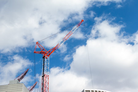 Tower crane and building under construction against blue sky with white cloudsの写真素材