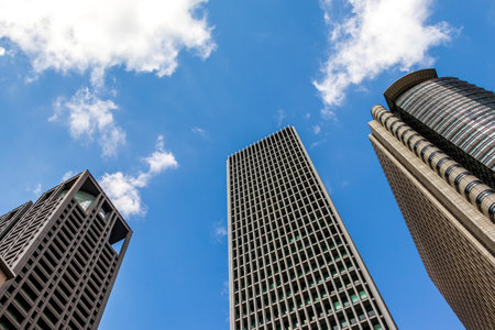 Low angle view of modern skyscrapers against blue sky with white clouds