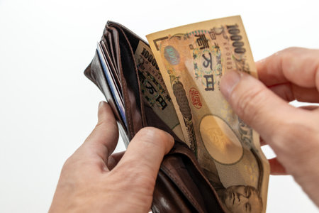 Man's hand holding a wallet with Japanese yen banknotes.の写真素材