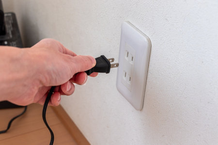 Electrician connecting a power cable to a socket on a white wall