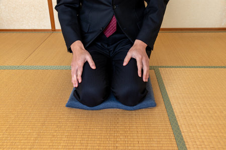 A man in a suit straight sitting on a cushion in a Japanese-style room with tatami flooringの写真素材