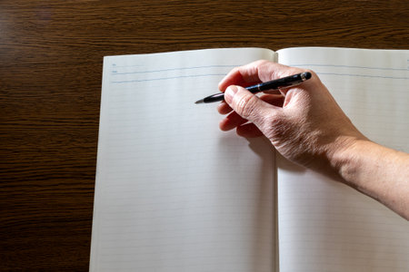 Write something with a pen in a notebook open on the deskの写真素材