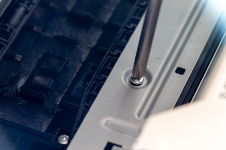Turning a screw on a machine part with a screwdriverの写真素材