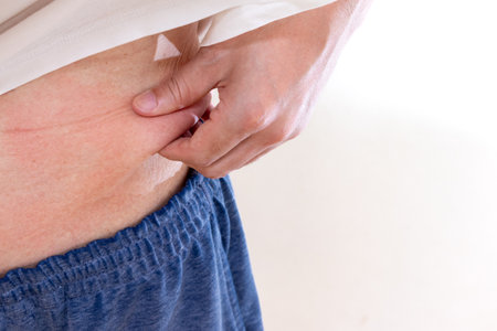 Middle-aged man pinching his belly fat with his fingersの写真素材