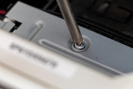 Turning a screw on a machine part with a screwdriver