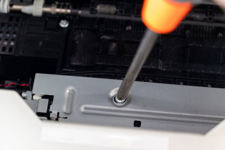 Turning a screw on a machine part with a screwdriver