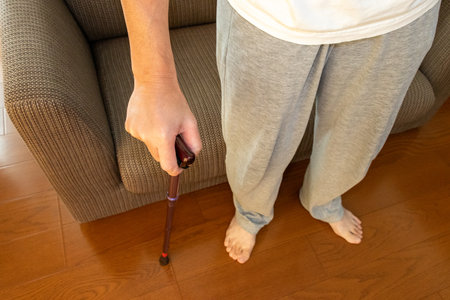 A person using a cane to stand up from a sofa