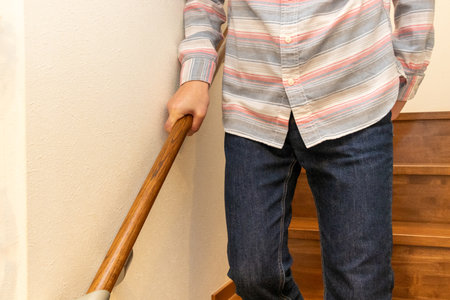 A man descending the stairs while holding the handrailの写真素材