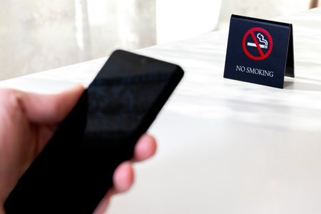 Using a smartphone at a non-smoking tableの写真素材