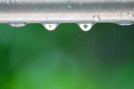 Drops of water dripping from a rain-soaked metal barの写真素材