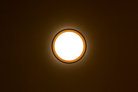 Circular lighting on the ceiling glowing in a dark roomの写真素材