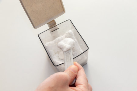 Scoop out the white sugar from the container with a measuring spoonの写真素材