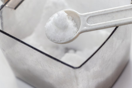 Scoop out the white sugar from the container with a measuring spoonの写真素材