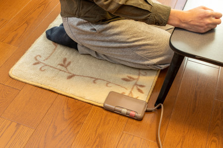 A man sitting on an electric carpet on the floorの写真素材