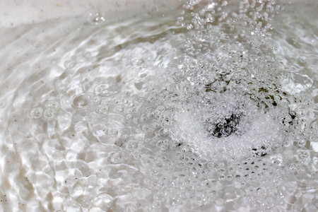 Water splashing down the sink drainの写真素材