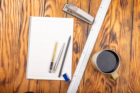 Office desk table with notepad, pen and coffee cup. Top view