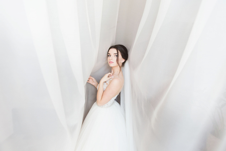 orgeous happy luxury stylish brunette bride near a window on the background of roomの写真素材