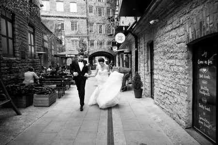 Bride and groom walking in the city, wedding day, marriage concept. Bride and groom in urban background. young couple in wedding day.の写真素材