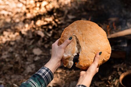 Closeup of fresh rustsic bread in a woman's hand. The background of the forest.の写真素材