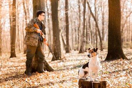Yang hunter with a dog on the forest.