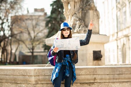 Young stylish woman walking on the old town street, travel with backpack and blue hat. Ukraine, Lviv.の写真素材