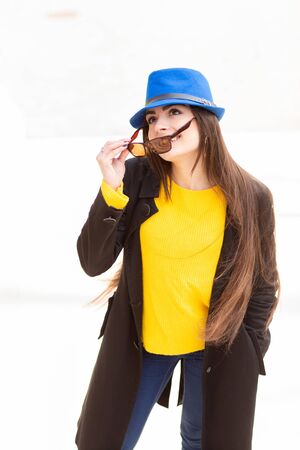 Portrait of a beautiful fashionable stylish woman in bright yellow sweater and blue hat. Street style shooting.の写真素材