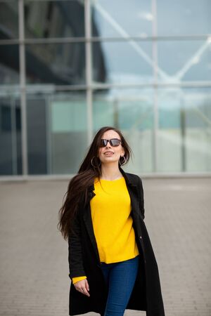 Portrait of a beautiful fashionable stylish woman in bright yellow sweater. Street style shooting.の写真素材