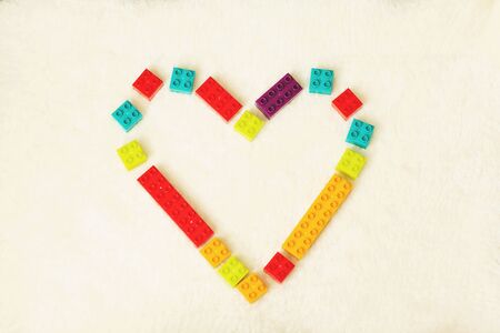 Bright heart made of colorful plastic bricks on white background. Early learning. Developing toys.