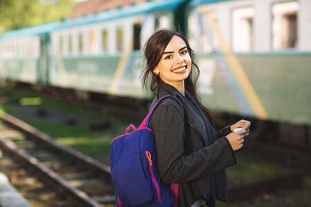 Woman with a backpack, near the train checks his ticket to the station platform.の写真素材