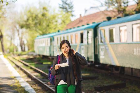 Woman with a backpack, near the train checks his ticket to the station platform.の写真素材