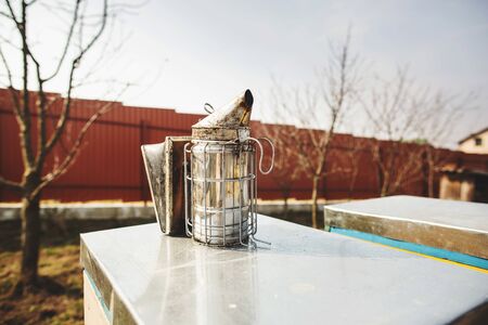 A beekeeping basic equipment - bee smoker - on the top of bee hive on a spring day. Close up.の写真素材