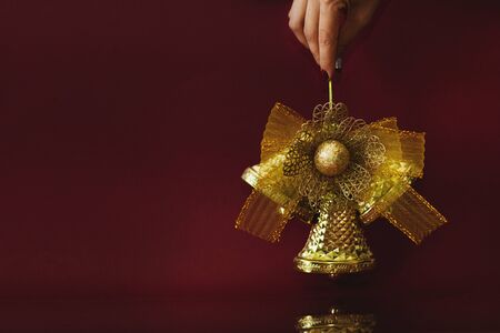 New Year's decoration. Festive golden bell on a burgundy background with a space for text.の写真素材