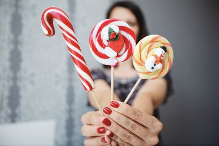 The girl holds colored Christmas candies in her hands. Sweets in the foreground. Christmas concept.の写真素材