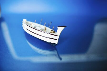 White little toy ship with shells on a blue background.の写真素材