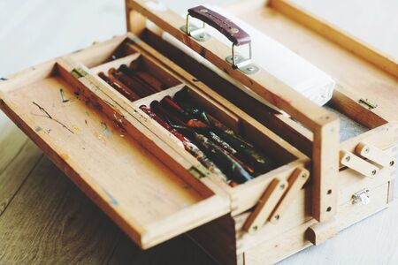 Wooden folding suitcase artist with brushes, paint and canvas. Background of a wooden floor.の写真素材