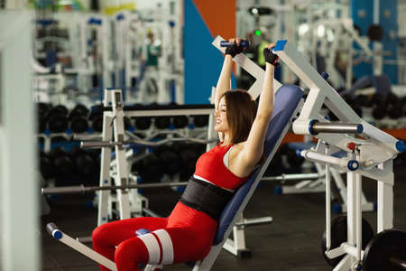 Sport everyday. Young healthy woman working out at gym. Doing exercises on the simulator.